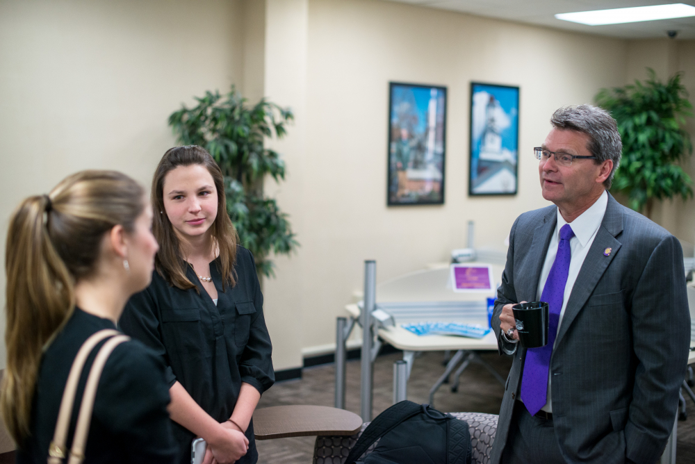 three people in business attire.  one holding a coffee cup.